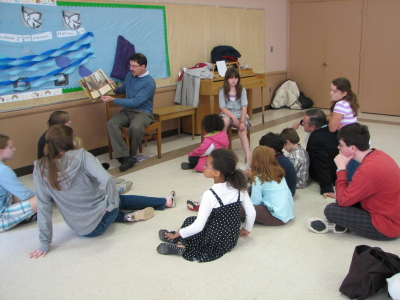 Kids and youth sitting on floor listening to story read by an adult