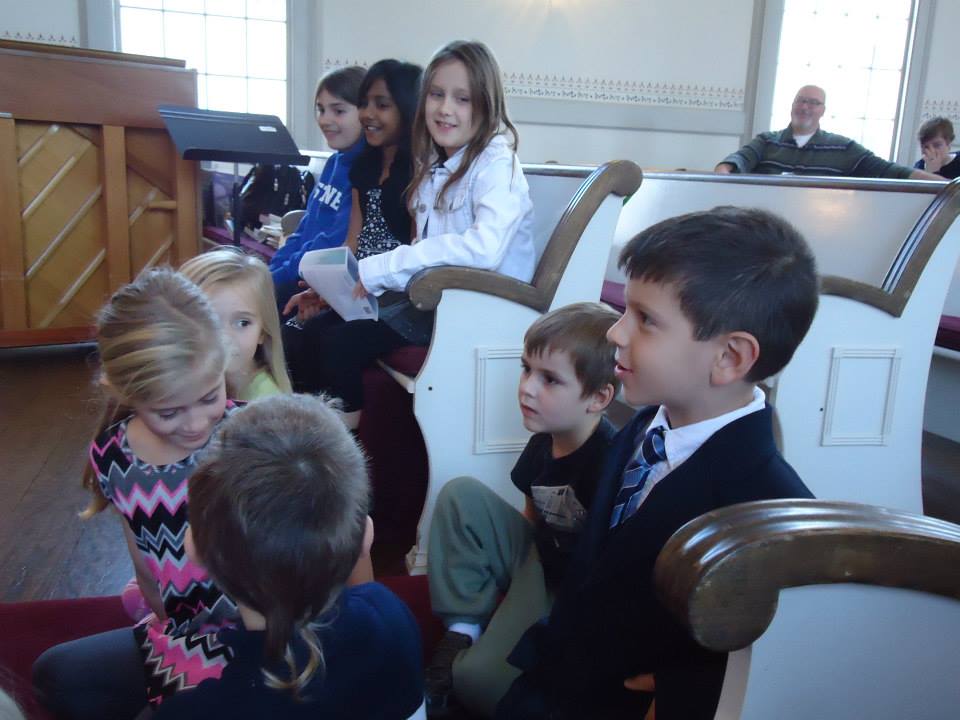 Kids sitting on the floor and pews at the front of the sanctuary